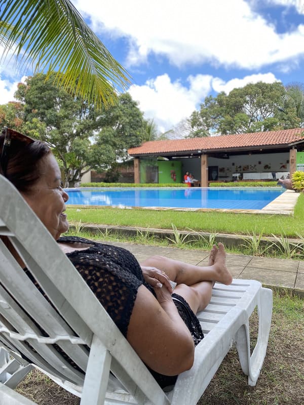 Idosa sorridente desfrutando da vista para a piscina na Casa de Repouso Rede Jardins, desfrutando de um ambiente seguro e acolhedor